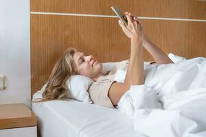 Woman using smartphone lying in bed photo