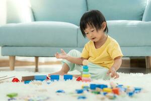 contento asiático niño jugando y aprendizaje juguete bloques niños son muy contento y emocionado a hogar. niño tener un genial hora jugando, actividades, desarrollo, atención déficit hiperactividad trastorno foto