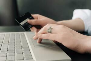 Graceful Online Shopping. Woman's Hands Hold Credit Card, Engaging in E-commerce with Laptop - Conceptual Image. Convenience of Online Shopping. Woman's Hands, Credit Card, and Laptop photo