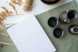 Book mockup design. Blank white book on dining table in asian style with tableware photo