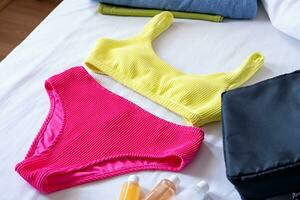 Travel cosmetics kit an bathing suit on bed , top view photo