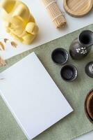 Book mockup design. Blank white book on dining table in asian style with tableware photo