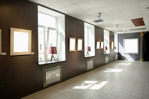 Blank picture frames on brown wall with glowing lamp, mock up photo