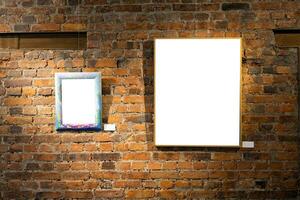 Blank picture frames on brick wall with glowing lamp, mock up photo