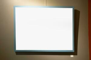 Blank picture frames on brown wall with glowing lamp, mock up photo