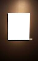 Blank picture frames on brown wall with glowing lamp, mock up photo