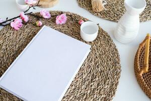 Book mockup design. Blank white book on dining table in asian style with tableware photo