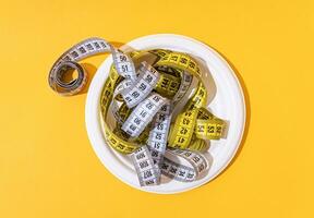 colorful measuring tapes top view on disposable plate on bright yellow background photo