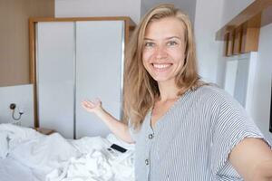 Happy woman showing her hotel room taking selfie photo