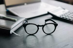 Organized Office Workspace with Glasses, Calculator, and Laptop. Financial Advisor, Budgeting, Tax, Savings, and Business Concept photo