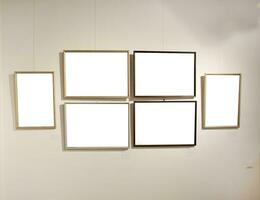 Blank picture frames on grey wall with glowing lamp, mock up photo