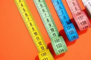 colorful measuring tapes top view on bright red background photo