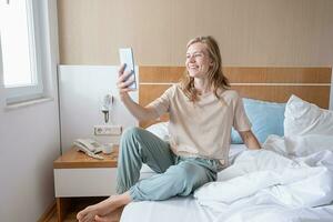 mujer utilizando teléfono inteligente acostado en cama foto
