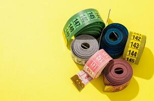 colorful measuring tapes high angle view on bright yellow background photo