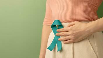 Ovarian and Cervical Cancer Awareness. Woman Holding Teal Ribbon on Lower Abdomen, Uterus, Female Reproductive System, Women's Health, PCOS and Gynecology photo