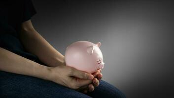Finanacial crisis Concepts. a Depressed Person Holding a Sad Face Piggy Bank in the Gloomy Room. Mental Health Affected by Recession and Loss of Savings photo