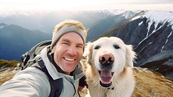 Hiking with the Dog, a Happy Smiling Man Taking Selfie with His Cute Golden Retriever Dog after Trail Trekking in Snow-Covered Mountain. Activities with Pet. photo