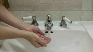 mulher lavagens mãos com água fechar-se dentro a afundar. pele higiene e proteção a partir de coronavírus, lavar dele dedos, Pare a espalhar do bactérias, salpicos e gotas video