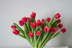 Red kung fu tulips stand in a glass vase on the table. Bouquet of flowers photo