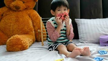 Asian boy playing with jigsaw puzzles on the bed joyfully video