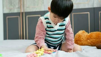 asiatico ragazzo giocando con sega puzzle su il letto con gioia video