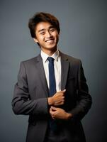 Smiling young man of Asian descent dressed in suit on gray background AI Generative photo