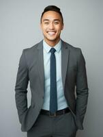 Smiling young man of Asian descent dressed in suit on gray background AI Generative photo