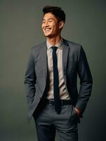 Smiling young man of Asian descent dressed in suit on gray background AI Generative photo