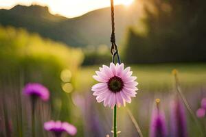 a pink flower is hanging from a string in a field. AI-Generated photo
