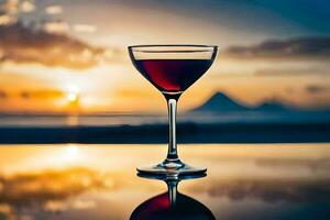 un vaso de rojo vino en un mesa en frente de un puesta de sol. generado por ai foto