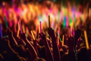 A close-up shot of hands holding glow sticks in the air at a rave party with a blurry crowd of people dancing in the background. Generative Ai photo