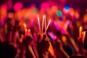 A close-up shot of hands holding glow sticks in the air at a rave party with a blurry crowd of people dancing in the background. Generative Ai photo