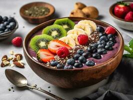A refreshing, fruit-filled smoothie bowl, brimming with an array of colorful berries, banana slices, and chia seeds. photo