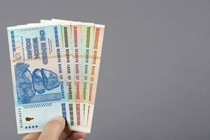 Old Zimbabwean money in the hand on a gray background photo