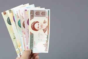 Old Iranian money in the hand on a gray background photo