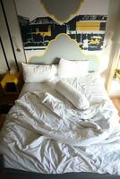 messy hotel bed. White pillow. White roll. white blanket. photo