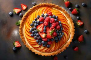 fresh fruit tart with fresh berries and peaches on a dark background photo