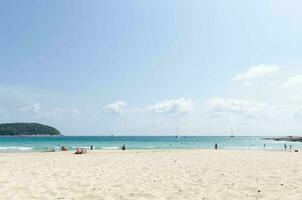 concurrido personas relajante baño de sol durante verano vacaciones a tropical playa en naiharn playa, phuket.gente en vacaciones en playa durante verano Brillo Solar tiempo de día foto