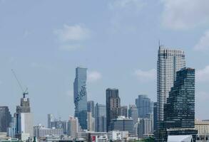 panorama landscape view of chaopraya river with river water boat transportation and background of bangkok city skyline with many highrise skyscraper among central district area in daytime photo