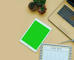 Top view of a streamlined work-from-home workspace with essential gadgets and a green screen setup. This minimalist arrangement is perfect for efficient remote work, virtual meetings, creatives. photo