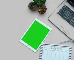 Top view of a streamlined work-from-home workspace with essential gadgets and a green screen setup. This minimalist arrangement is perfect for efficient remote work, virtual meetings, creatives. photo