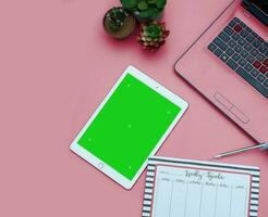 Top view of a streamlined work-from-home workspace with essential gadgets and a green screen setup. This minimalist arrangement is perfect for efficient remote work, virtual meetings, creatives. photo