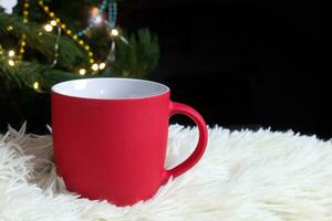 blanco rojo jarra con Navidad árbol en fondo, estera té o café taza con Navidad y nuevo año decoración,horizontal burlarse de arriba con cerámico jarra para caliente bebidas, vacio regalo impresión modelo foto