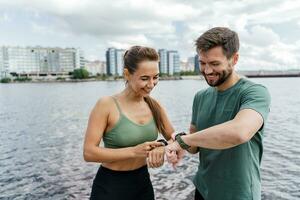 utilizar un aptitud reloj y un aplicación masculino y hembra Atletas tren en aptitud y correr. equipo ejercicios de un joven Pareja. personas en ropa de deporte juntos, físico educación y Deportes. foto