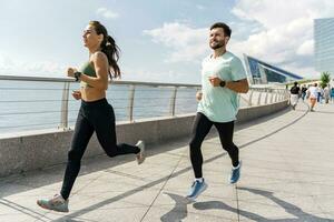 personas en ropa de deporte juntos corredores, físico educación y Deportes. corriendo hombre y mujer tren. utilizando inteligente relojes y un aptitud aplicación equipo ejercicios de un joven Pareja. foto