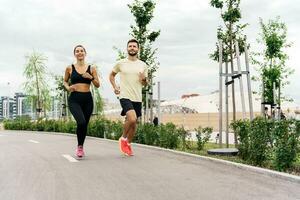 A running instructor and a client are training fitness outdoors. A woman and a man are friends in fitness clothes for sports. People use fitness watches and running shoes. photo