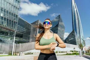 el corriendo rutina de ejercicio entrenador usos un aptitud reloj y un aplicación para ejercicio resultados. físico educación es un sano estilo de vida. hembra atleta en aptitud ropa, foto