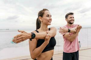 Athletes train together. A woman and a man are getting ready for a run. Fitness friends do exercises for a healthy lifestyle. Use a fitness watch and wristband to work with the app. photo