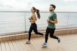 personas en ropa de deporte juntos, físico educación y Deportes. atlético hombre y mujer tren en aptitud y correr. utilizando inteligente relojes y un aptitud aplicación equipo ejercicios de un joven Pareja. foto