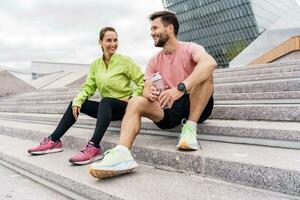 Break coach and client workout fitness outdoors. A woman and a man are friends in fitness clothes for sports. People use fitness watches and running shoes. photo